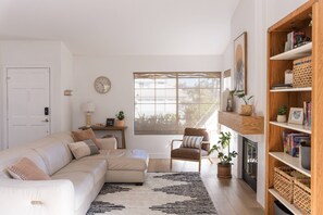 Relax in this cozy living space with a comfortable sofa, armchair, and large window offering a view of the outdoors.
