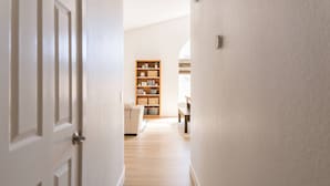 Un couloir avec une bibliothèque en bois, une porte blanche et un plancher de couleur claire.
