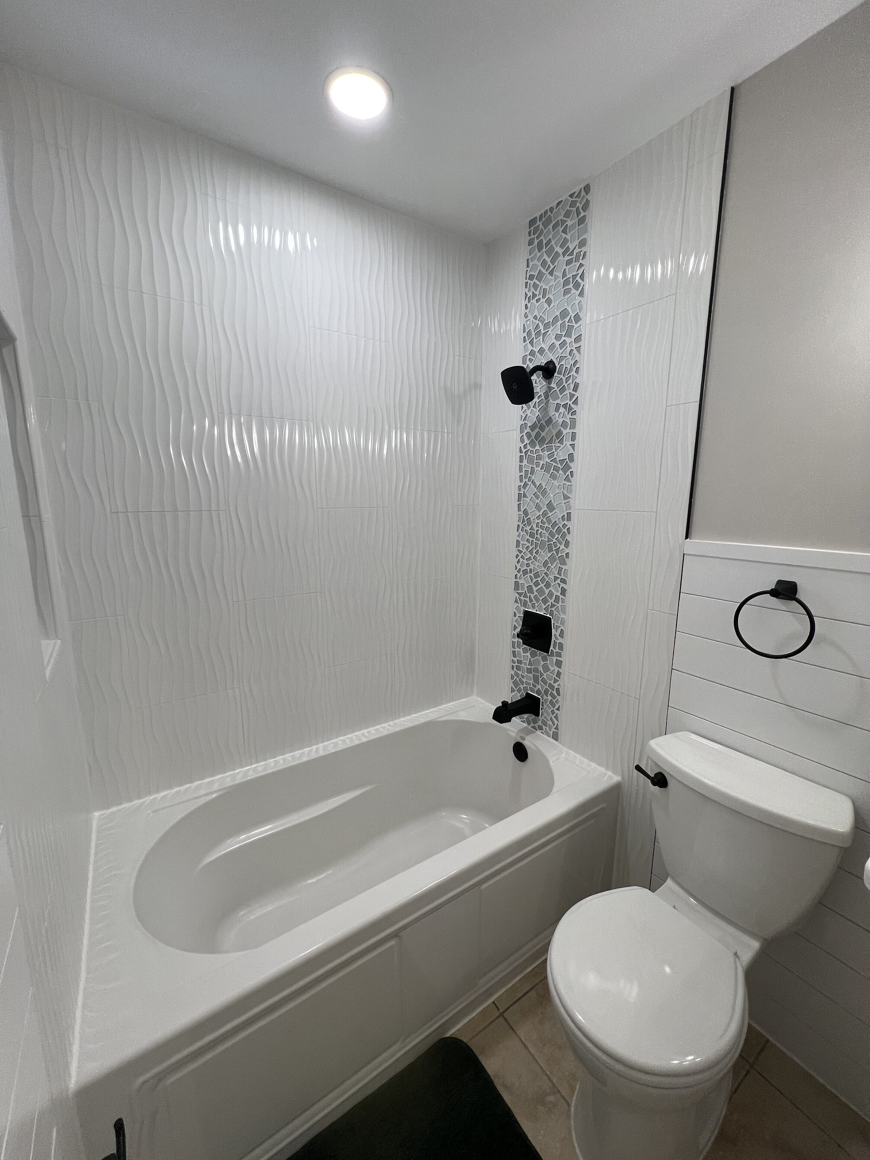 A bathroom with a white bathtub, a toilet, and a shower area.