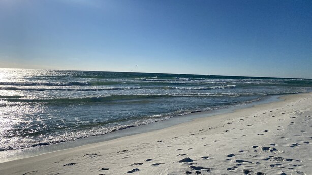 A beach with footprints in the sand and a clear sky.