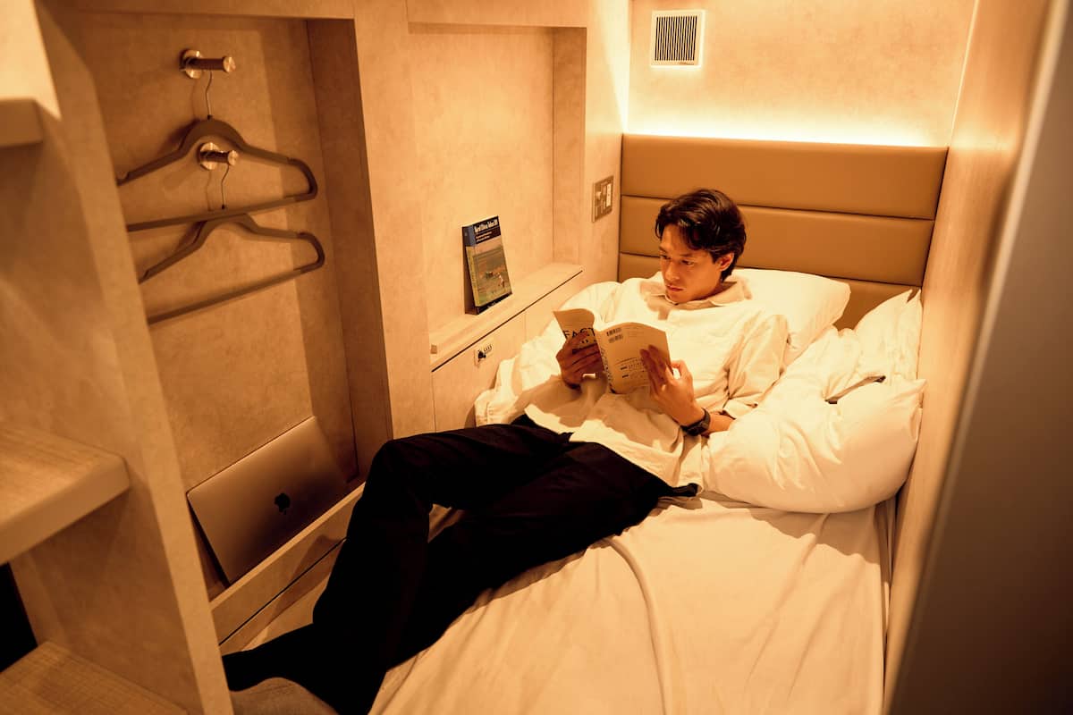 A hotel room with a bed, a laptop, and a book.