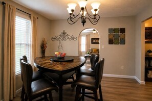 A dining area with a round table, chairs, a chandelier, and a view into another room. - Cozy, Contemporary Haven Near Historic Downtown (Savannah)