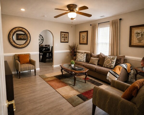 A living room with a ceiling fan, a sofa, a coffee table, and a chair.