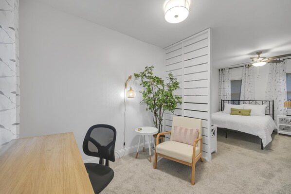 Un dormitorio con cama, mesita de noche, lámpara y una silla.