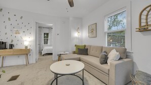 Una sala de estar moderna con un sofá color beige, una mesa de centro redonda y un ventilador de techo.