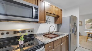 Una cocina con armarios de madera, un refrigerador de acero inoxidable, un microondas y un lavamanos.