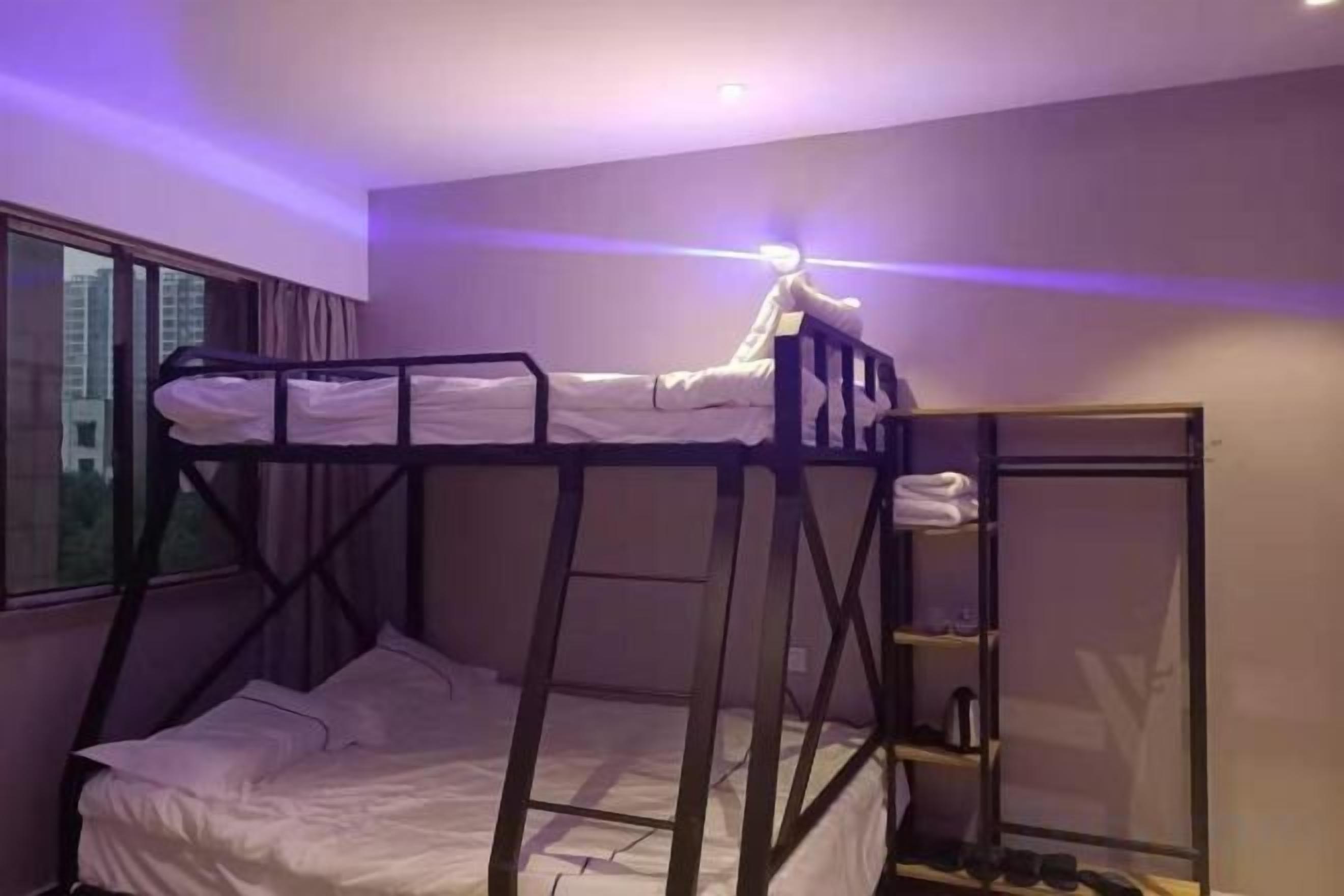 A bunk bed room with a window, a nightstand, and a mirror.