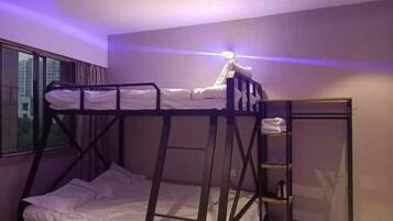 A bunk bed room with a window, a nightstand, and a mirror.