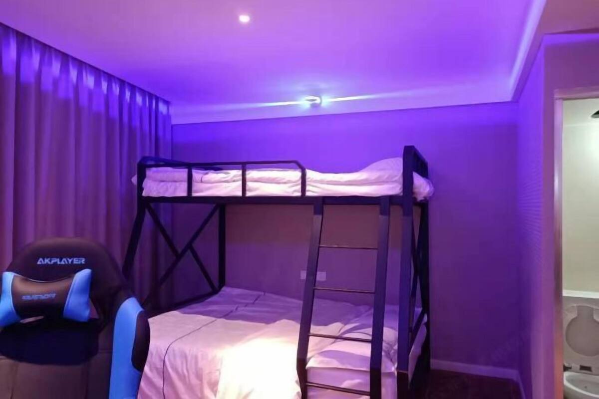 Habitación con literas, una escalera, una lámpara en el techo y una cortina.