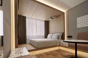 A modern hotel room with a bed, a sofa, a small table, and a TV.
