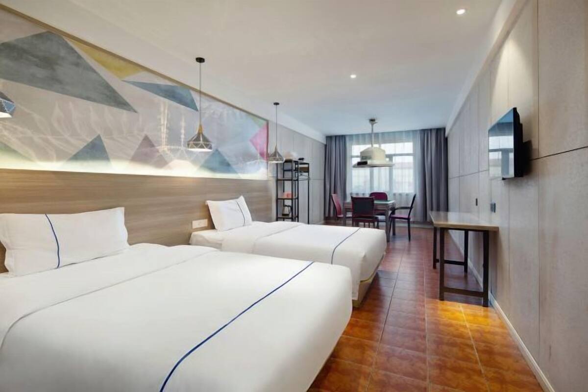 Habitación de hotel con dos camas, un escritorio y una silla.
