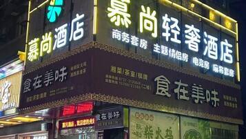 Un hotel con letreros de neón que indica que ofrece alojamiento para negocios y ocio, con habitaciones y un restaurante.
