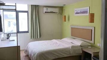 Una habitación de hotel con una cama, una mesita de noche y un ventanal con cortinas.