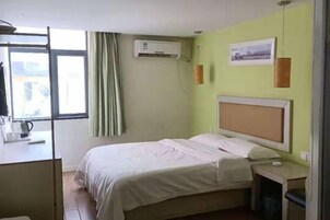 Una habitación de hotel con una cama, una mesita de noche y un ventanal con cortinas.