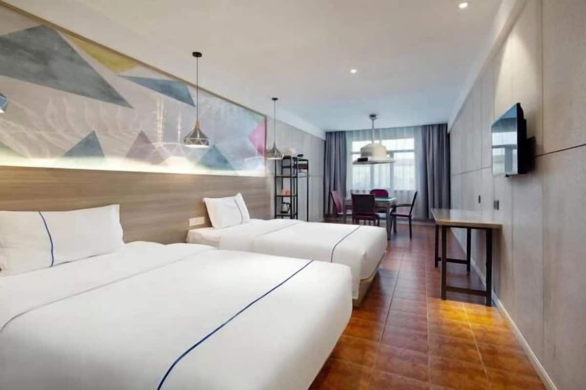 Habitación de hotel con dos camas, un escritorio y una silla.
