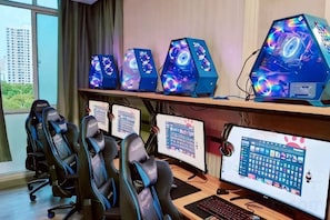 A gaming setup with multiple monitors, gaming chairs, and a desk. - Mushang hotel (Yiyang)