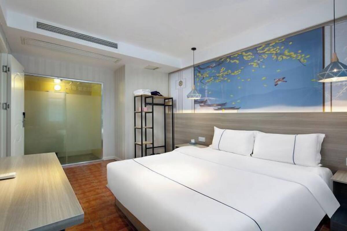 Una habitación de hotel con cama, escritorio, armario y pared decorada con un mural.