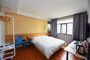 A hotel room with a bed, desk, chair, and a window with curtains. - Mushang hotel (Yiyang)