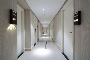 A hotel corridor with illuminated room numbers on the walls, a clean tiled floor, and a straight path leading to the end of the corridor. - Mushang hotel (Yiyang)