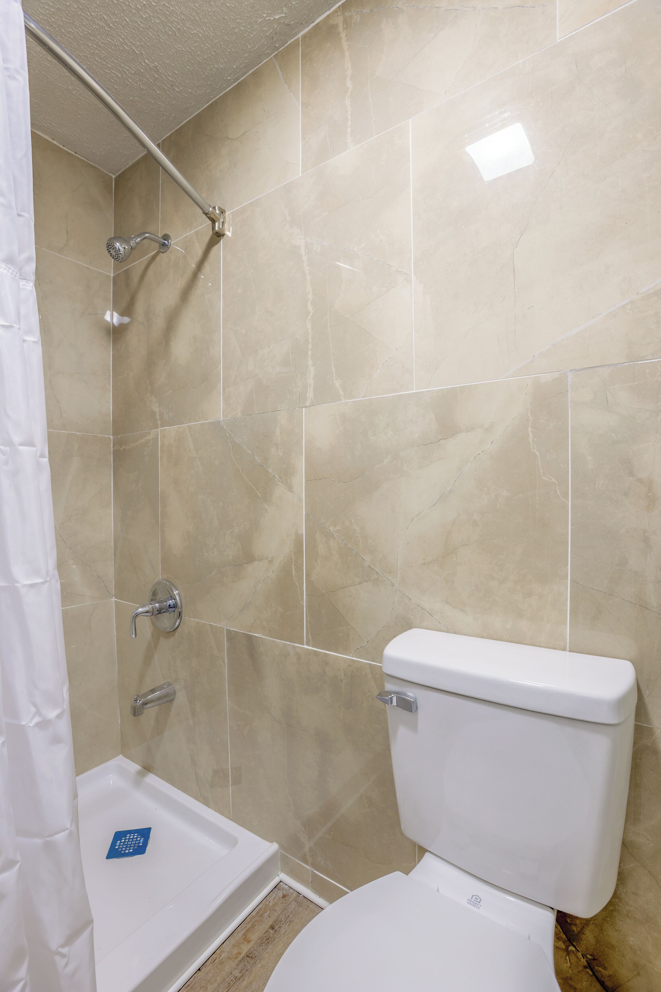 Un baño con ducha, inodoro y un lavabo pequeño.