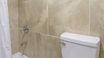 Un baño con ducha, inodoro y un lavabo pequeño.