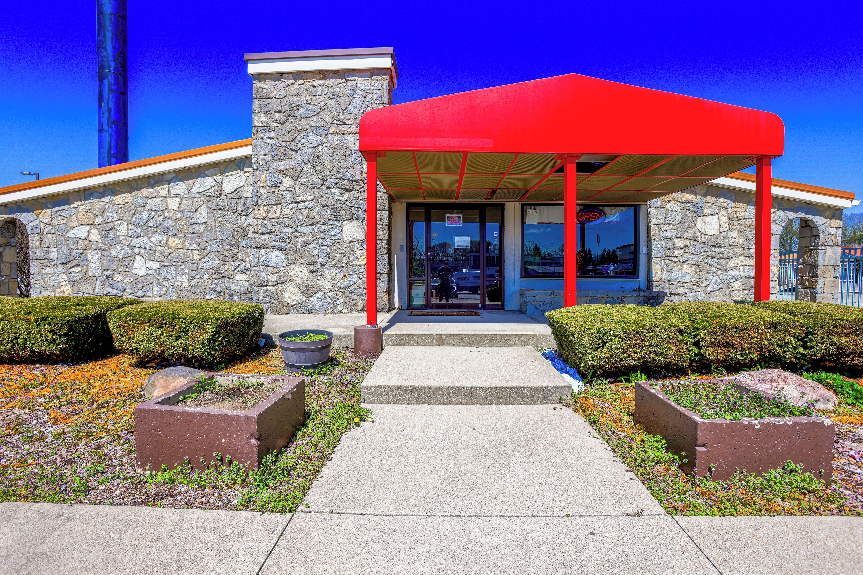 A building with a stone facade, a red awning, and a clear sky.