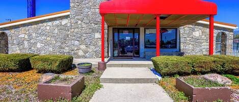 A building with a stone facade, a red awning, and a clear sky.
