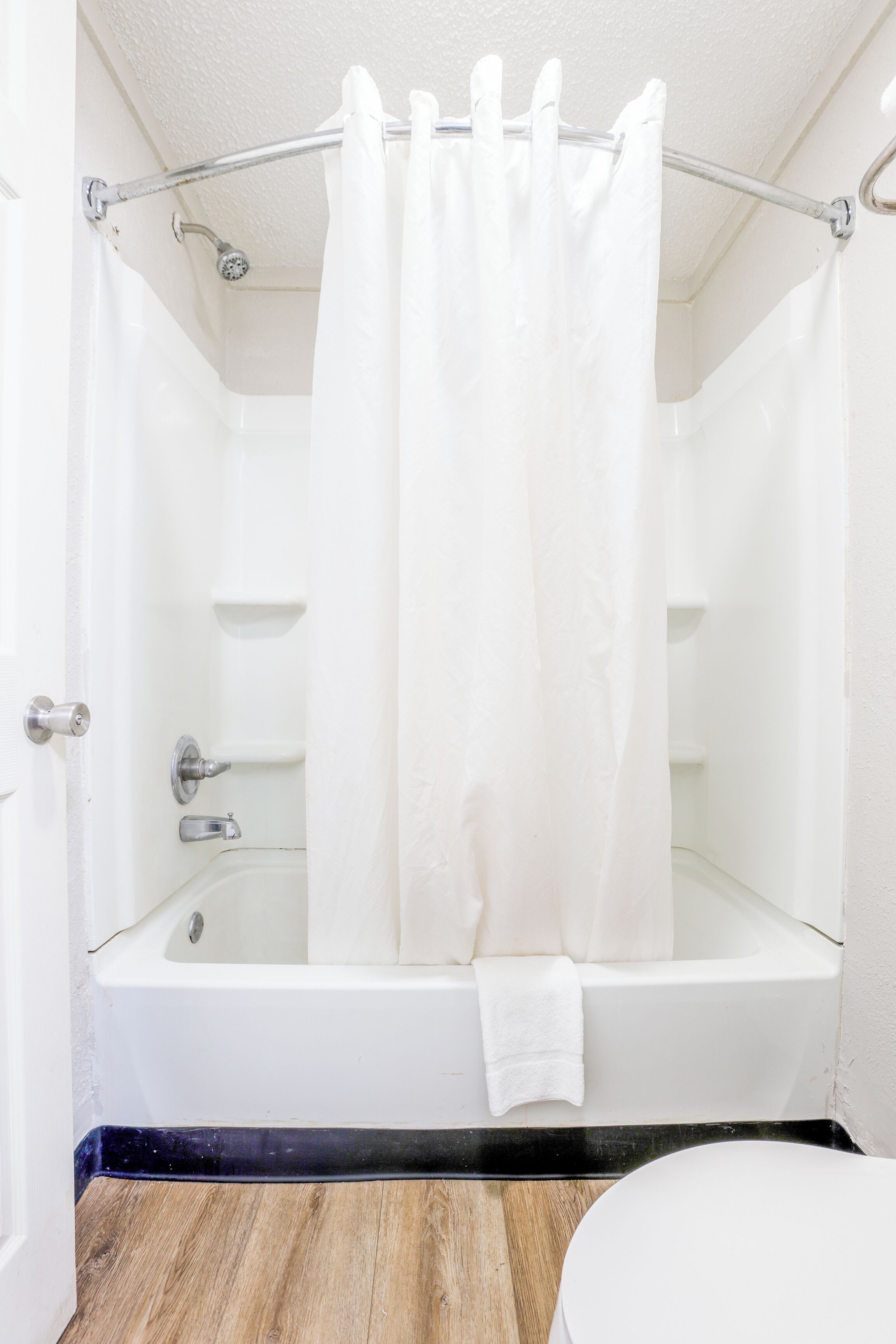 A bathroom with a bathtub, a shower curtain, and a toilet.