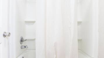 A bathroom with a bathtub, a shower curtain, and a toilet.