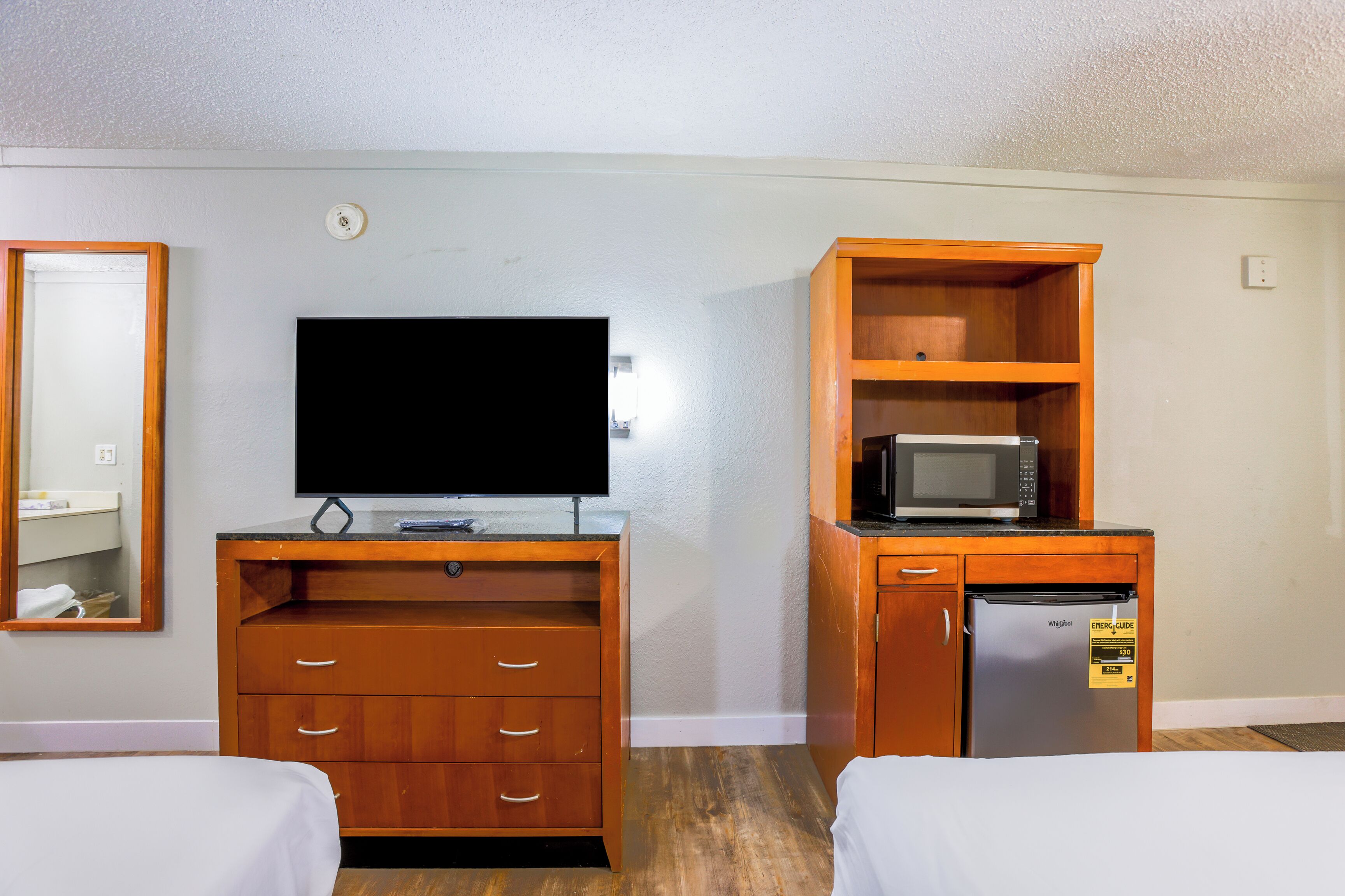 Ein Hotelzimmer mit einem Holztisch, einem Flachbildfernseher, einer Mikrowelle und einem Minikühlschrank.
