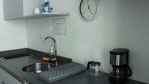 Uma cozinha com pia, cafeteira e relógio na parede.