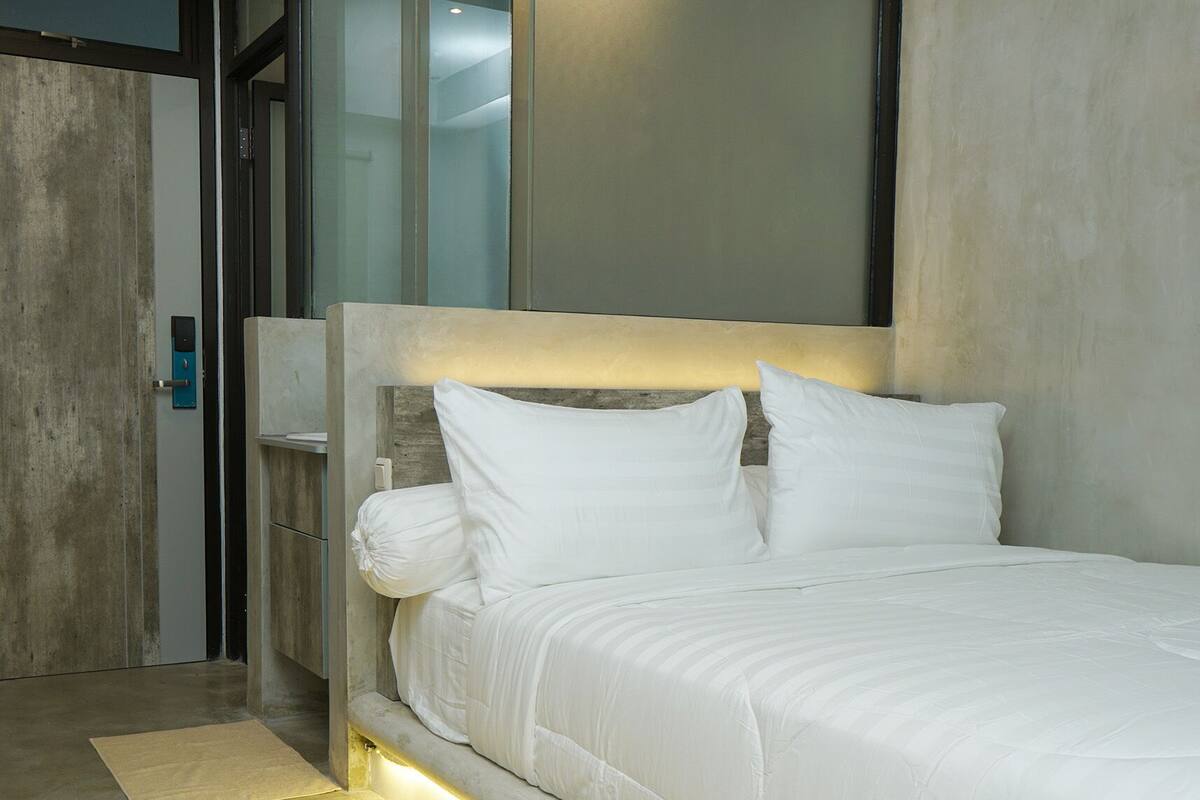A modern bedroom with a large bed, a bedside table, and a built-in headboard.