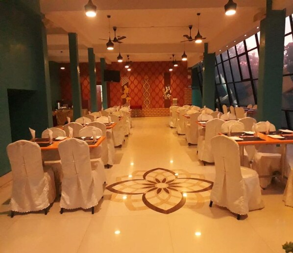 A banquet hall with tables set for a formal event, featuring a central floral design on the floor. - Golden Nest (Yercaud)