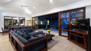 Ein geräumiges Wohnzimmer mit einem großen Sofa, einem Essbereich und einem Fernseher auf einem Holzboden.
