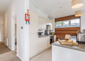 Eine moderne Küche mit weißen Schränken, einem eingebauten Ofen, einer Mikrowelle und einer Wand mit Holzakzenten.