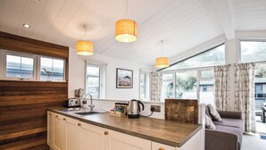 Cocina moderna con armarios de madera, una isla central, luces colgantes y vistas al exterior.