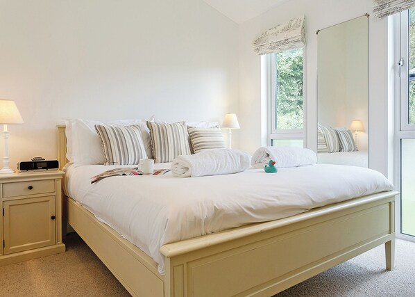 A bedroom with a bed, bedside tables, lamps, and a window with a view. - 4 bedroom accommodation in Mullion Cove, Helston (Mullion Cove, Helston)