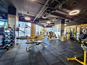 A gym with various exercise equipment, large windows, and a tiled floor.