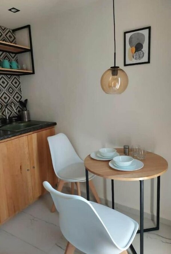 Een moderne keuken met een houten kast, een ronde tafel met witte stoelen en een hangende lamp.