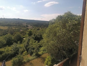 Ein Balkon mit Blick auf eine ländliche Landschaft, Bäume und Felder.