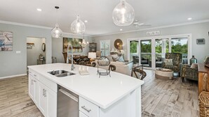 Una cocina amplia con una isla grande, luces colgantes y vistas al exterior.