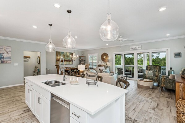A spacious kitchen with a large island, pendant lights, and a view to the outdoors.
