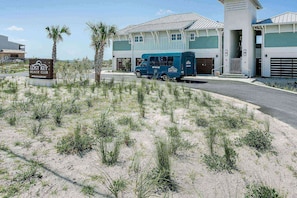 Un club de platja amb un cartell que diu "Lost Key Beach Club", un camió blau estacionat al davant i un edifici amb teulada verda.