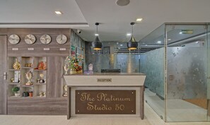 A reception desk labeled "The Platinum Studio 50" with clocks on the wall and a glass door to the right. - Treebo The Platinum Studio 50 (Barasat)