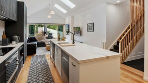 Una cocina moderna con una isla central, electrodomésticos integrados y un comedor con sofá y mesa de centro.