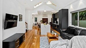 Una sala de estar moderna con un sofá de cuero negro, una mesa de centro de madera y un televisor montado en la pared.