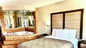 A hotel room with a large bed, a separate bathroom with a bathtub, and a large mirror. - Bridgeview Inn Chicago Area (Bridgeview)