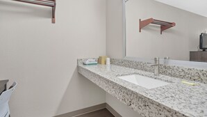 A bathroom with a granite countertop, a sink, a mirror, and towel racks. - Bridgeview Inn Chicago Area (Bridgeview)