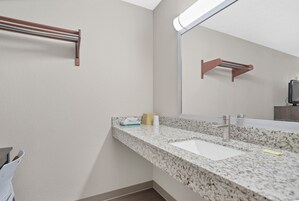 Un baño con encimera de granito, lavabo, espejo y toalleros.
