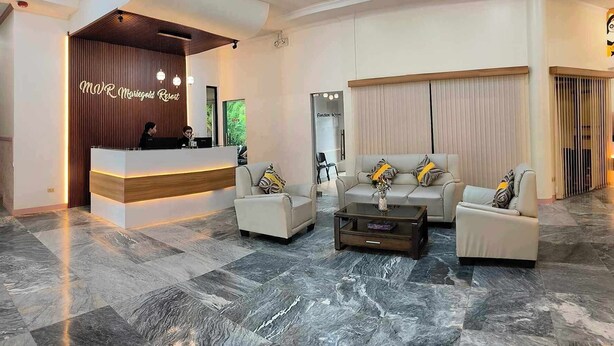 A hotel lobby with a reception desk, seating area, and a chandelier. - MVR Mariegold Resort Inc. (Lapu-Lapu)